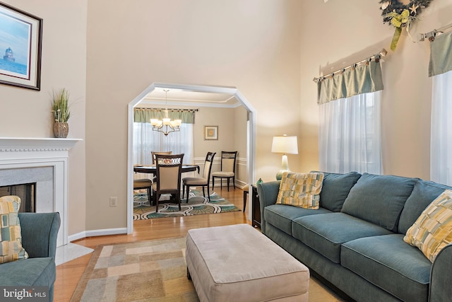 living room with an inviting chandelier, light hardwood / wood-style flooring, ornamental molding, and a high ceiling