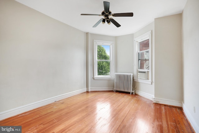 spare room featuring radiator, ceiling fan, and light wood-type flooring