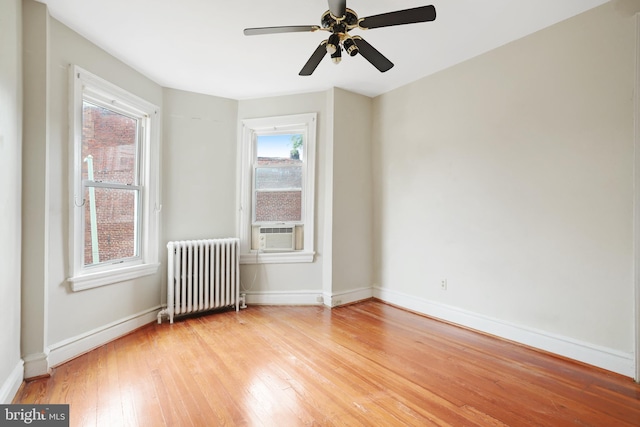 empty room featuring radiator, ceiling fan, wood-type flooring, and cooling unit