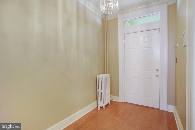 foyer with radiator heating unit, light wood-type flooring, a chandelier, and crown molding