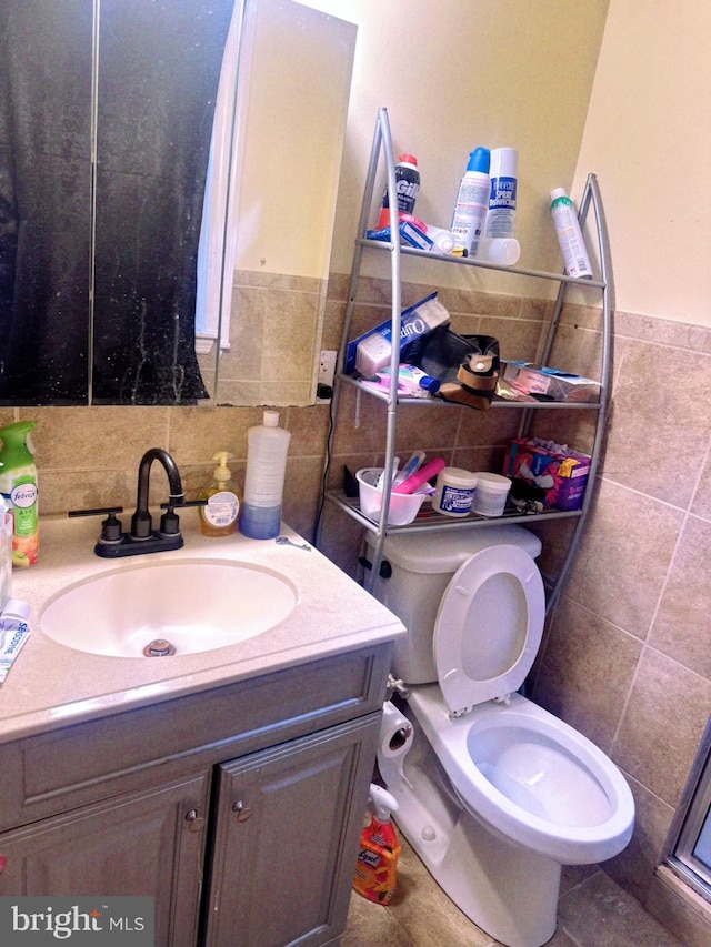 bathroom featuring vanity, tile walls, and toilet