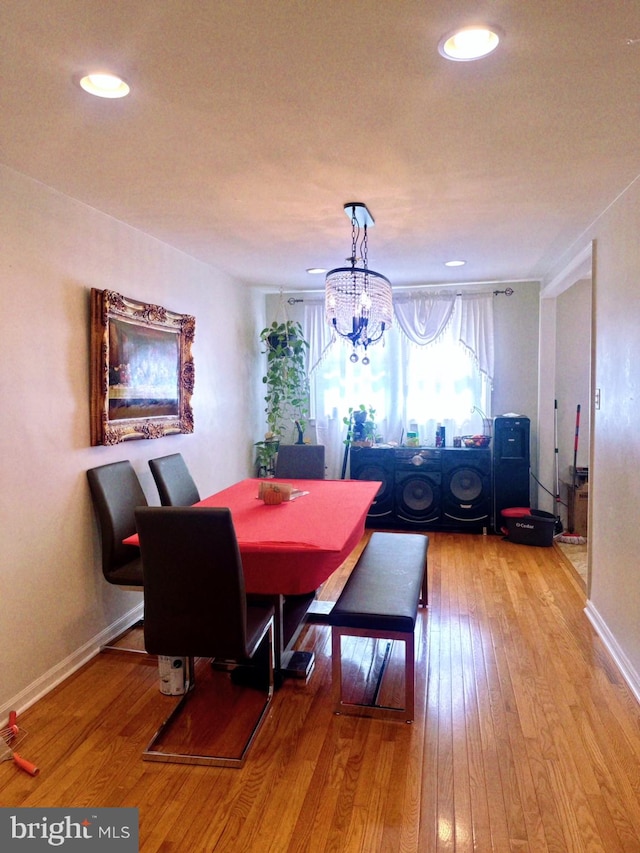 dining space with light hardwood / wood-style flooring and a notable chandelier