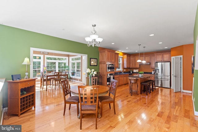 dining space with a notable chandelier, light wood-type flooring, and sink