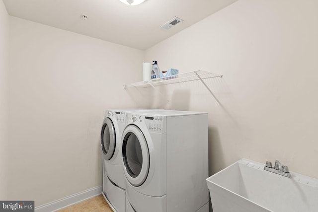 clothes washing area featuring washer and dryer, sink, and light tile patterned floors