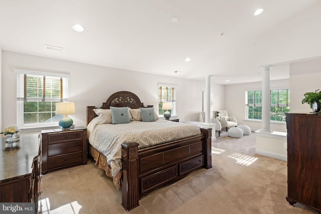 carpeted bedroom with decorative columns and multiple windows