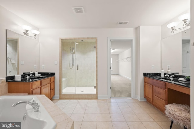 bathroom with an inviting chandelier, vanity, plus walk in shower, and tile patterned flooring