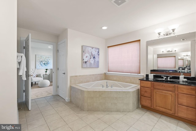 bathroom featuring tile patterned flooring, tiled tub, and vanity