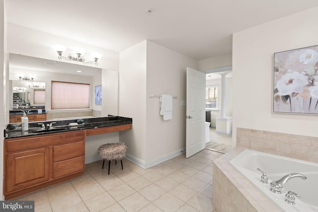 bathroom featuring vanity, a relaxing tiled tub, decorative columns, and tile patterned flooring