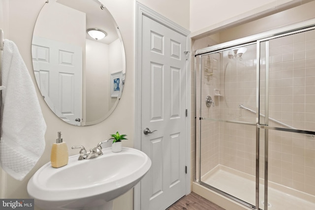 bathroom with walk in shower, sink, and wood-type flooring