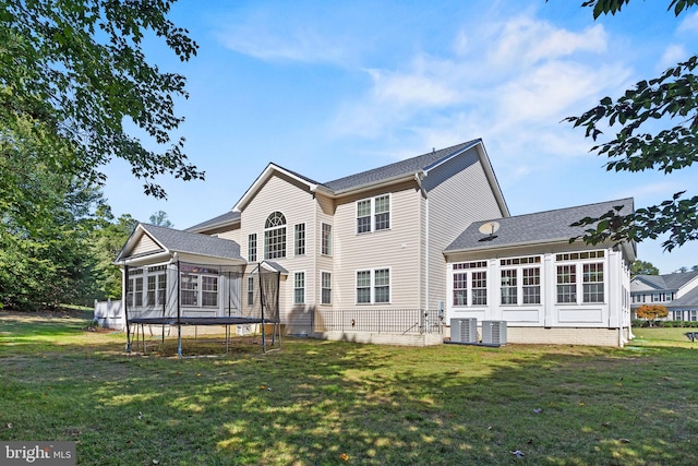 rear view of house with central AC unit, a sunroom, and a yard