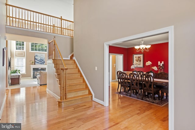 stairway featuring ornamental molding, a towering ceiling, hardwood / wood-style floors, and a chandelier