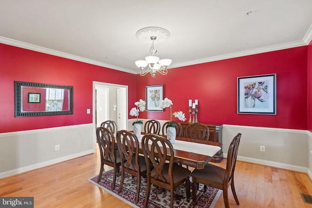 dining room featuring wood-type flooring, a chandelier, and ornamental molding