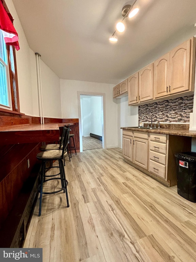 kitchen with light brown cabinets, light wood-type flooring, sink, and tasteful backsplash