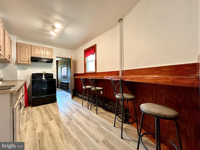 kitchen with a breakfast bar, light wood-type flooring, light brown cabinetry, black electric range oven, and sink