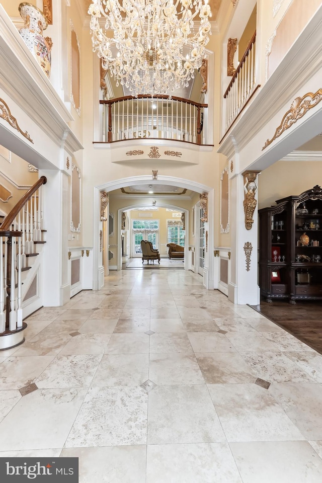 foyer featuring a high ceiling, a chandelier, wood-type flooring, and crown molding