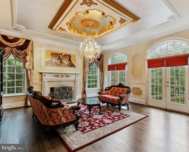 living room with ornamental molding, an inviting chandelier, a raised ceiling, and dark wood-type flooring