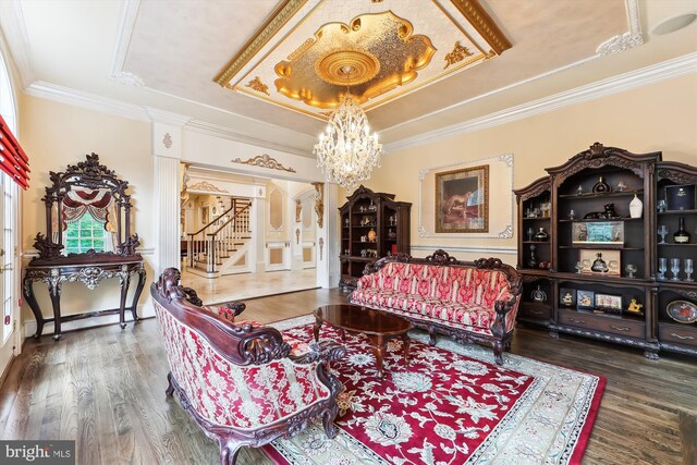 living room with a notable chandelier, a tray ceiling, crown molding, and dark hardwood / wood-style flooring