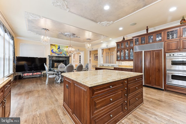 kitchen featuring paneled refrigerator, a chandelier, a center island, light hardwood / wood-style flooring, and double oven