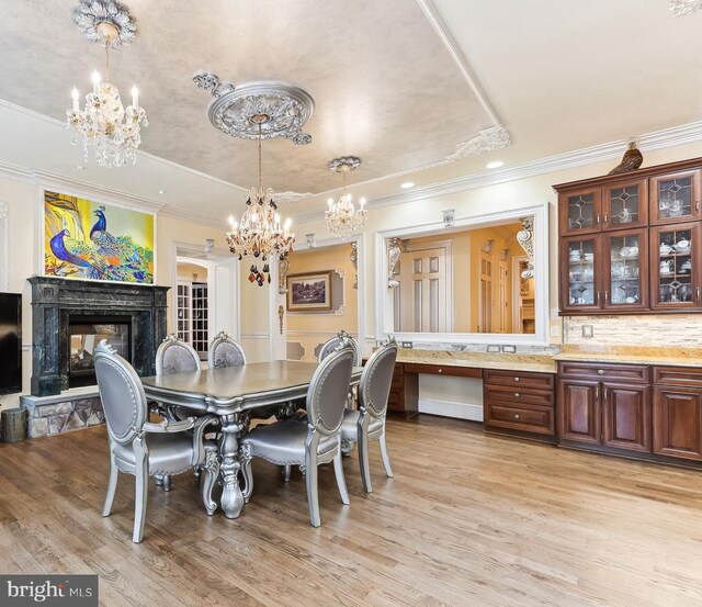 dining space with light hardwood / wood-style flooring, a multi sided fireplace, a notable chandelier, and crown molding