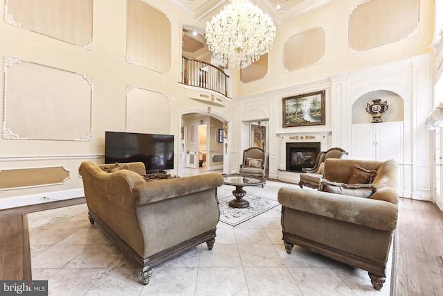 living room featuring built in shelves, a towering ceiling, and a chandelier