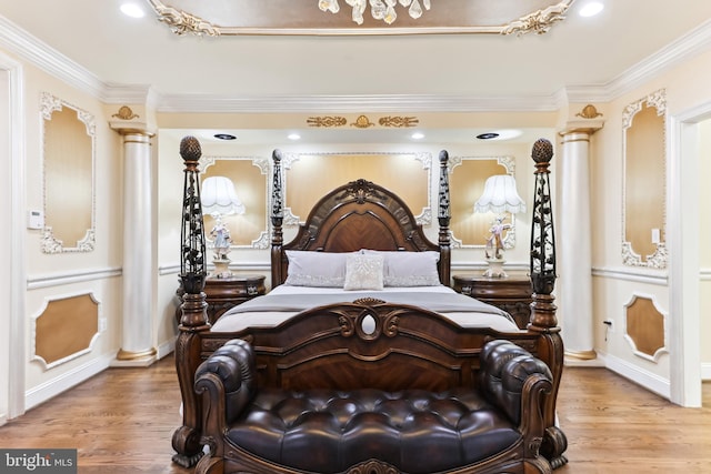 bedroom featuring ornate columns, ornamental molding, and hardwood / wood-style flooring