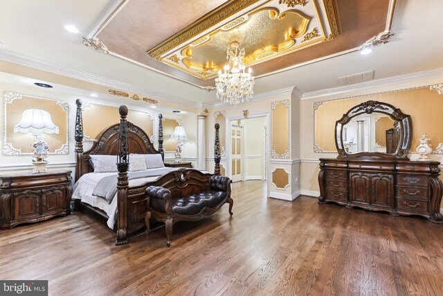 bedroom with wood-type flooring, a raised ceiling, crown molding, and ornate columns