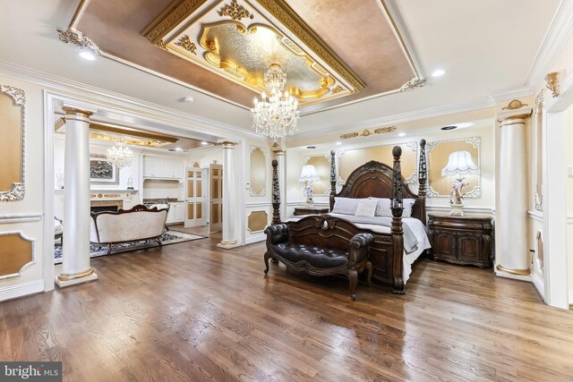 bedroom with wood-type flooring, crown molding, an inviting chandelier, and ornate columns