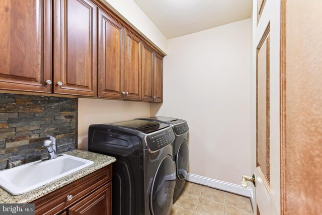 clothes washing area with washer and clothes dryer, light tile patterned flooring, sink, and cabinets