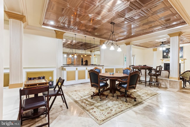 dining space with ornamental molding, ceiling fan, a fireplace, and ornate columns