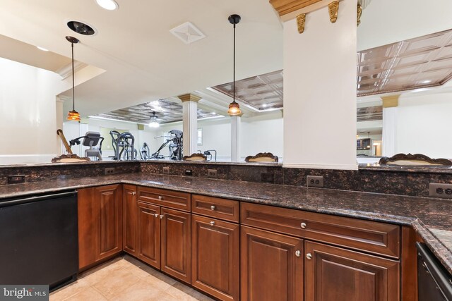 kitchen featuring dark stone counters, black dishwasher, decorative light fixtures, and ornate columns