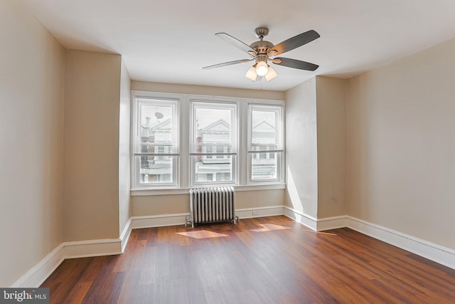 empty room with radiator, dark hardwood / wood-style floors, and ceiling fan