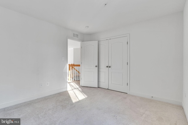 unfurnished bedroom featuring light colored carpet and a closet