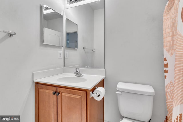 bathroom with toilet, vanity, and a shower with curtain