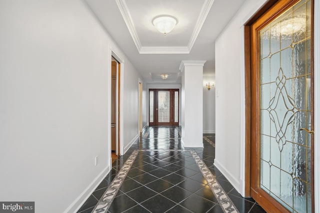 hall featuring ornamental molding, a tray ceiling, and dark tile patterned floors