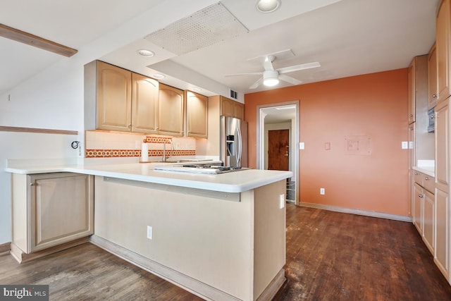 kitchen with tasteful backsplash, dark wood-type flooring, kitchen peninsula, and appliances with stainless steel finishes