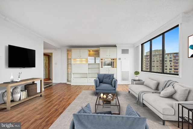 living room featuring ornamental molding, hardwood / wood-style floors, and a textured ceiling