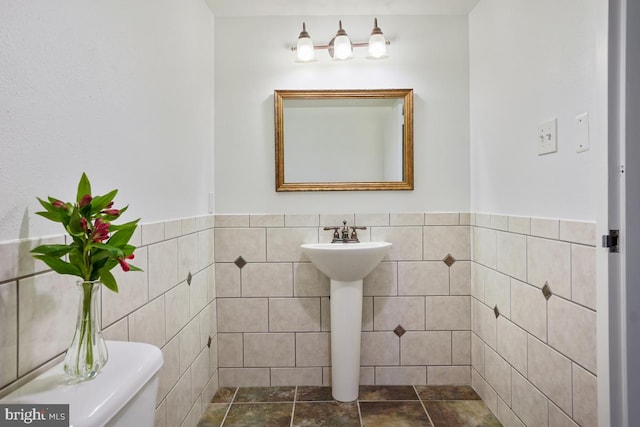 bathroom featuring toilet, tile patterned flooring, and tile walls