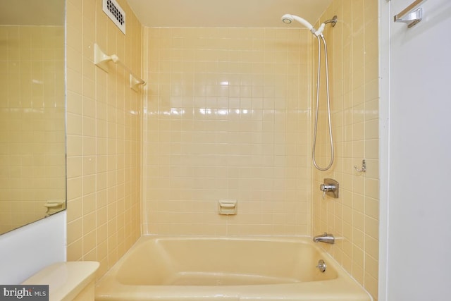 bathroom with tiled shower / bath combo and toilet