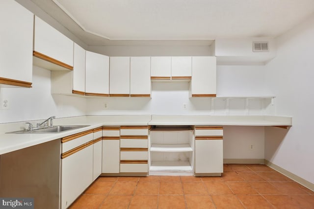 kitchen featuring white cabinetry, light tile patterned flooring, and sink