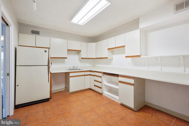 kitchen featuring sink, light tile patterned floors, white cabinets, and white refrigerator