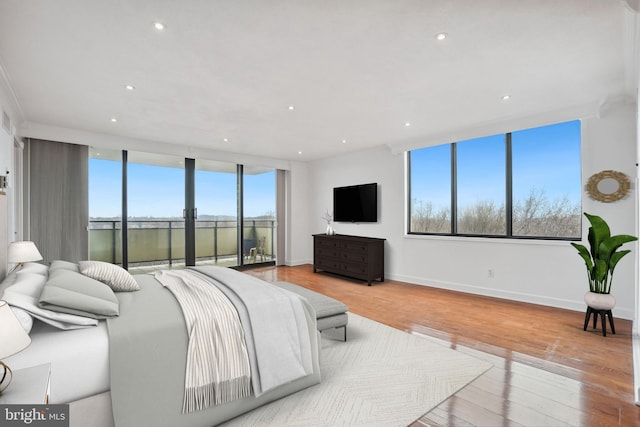 bedroom featuring expansive windows, access to exterior, and light hardwood / wood-style floors