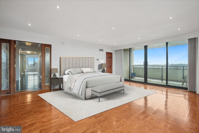 bedroom featuring a wall of windows, light wood-type flooring, and access to outside