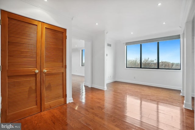 unfurnished bedroom featuring ornamental molding, light wood-type flooring, and a closet