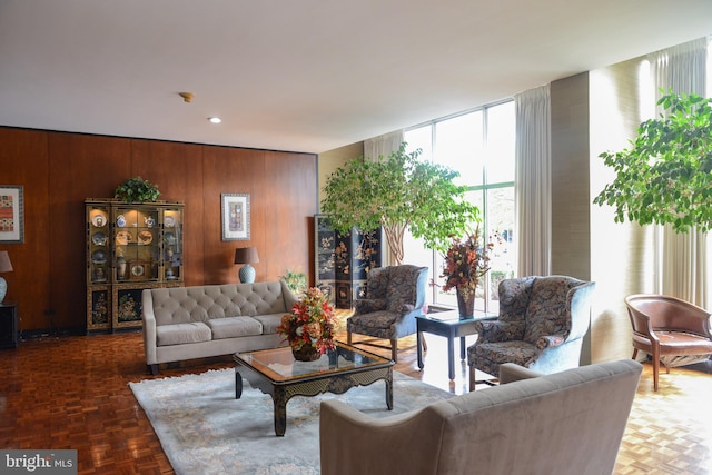 living room featuring wooden walls and dark parquet floors