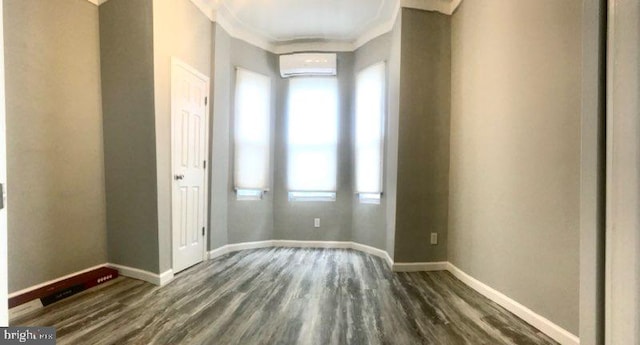 empty room featuring ornamental molding, a wall mounted AC, and dark wood-type flooring