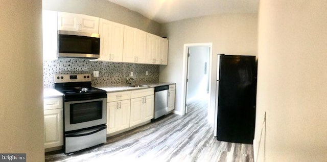 kitchen with white cabinets, appliances with stainless steel finishes, light hardwood / wood-style floors, and tasteful backsplash