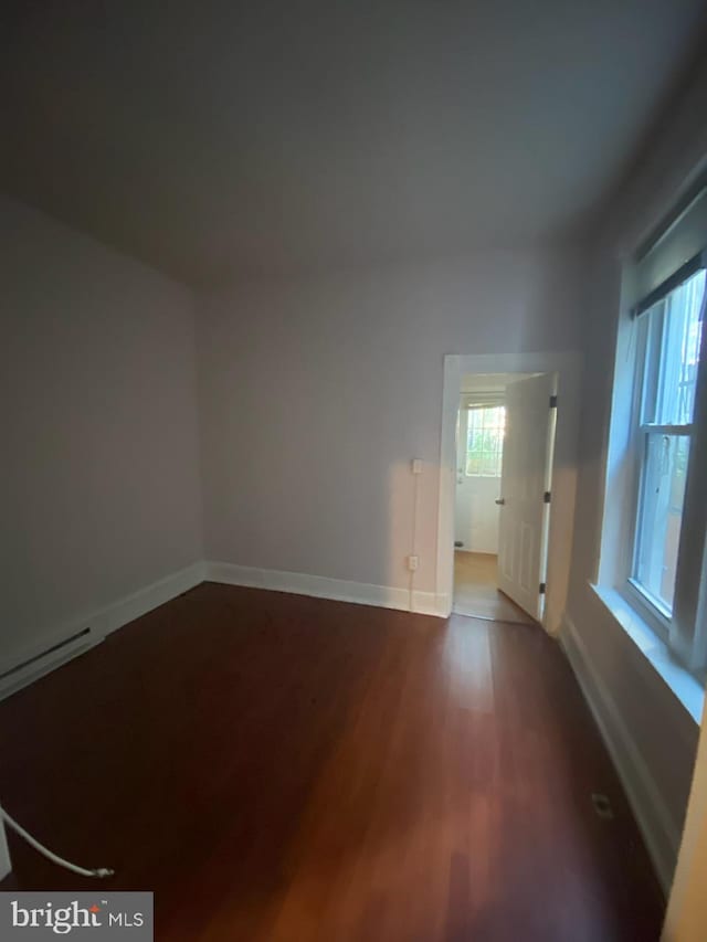 empty room with baseboard heating and hardwood / wood-style flooring