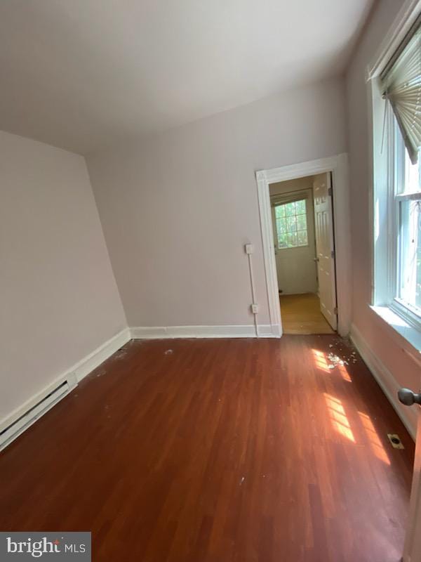 empty room featuring hardwood / wood-style flooring and a baseboard heating unit