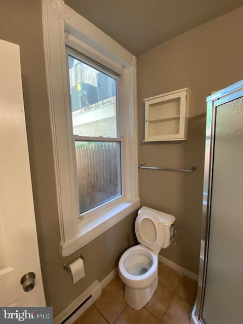 bathroom featuring tile patterned floors, toilet, an enclosed shower, and baseboard heating