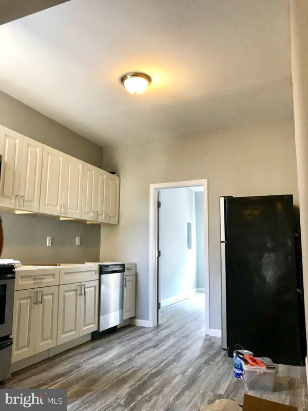 kitchen with white cabinetry, black refrigerator, stainless steel dishwasher, and range